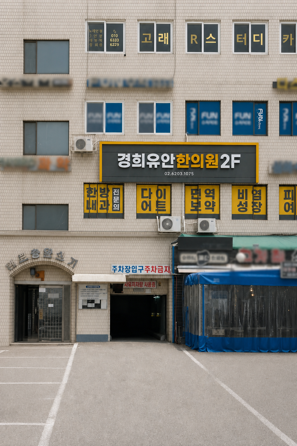 경희유안한의원 간판과 왼쪽 사람 출입구, 건물 주차장 입구가 보이는 개포종합상가 외관